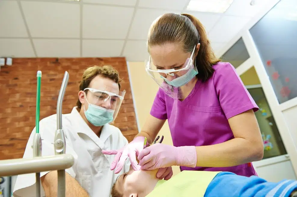 Child Being Treated Under Sedation By Dentist & His Assistant