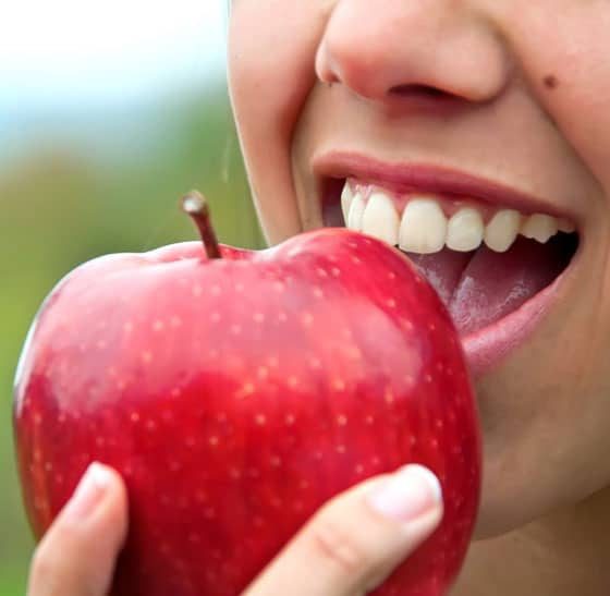 Women Eating An Apple — Suncoastdental In Maroochydore, QLD